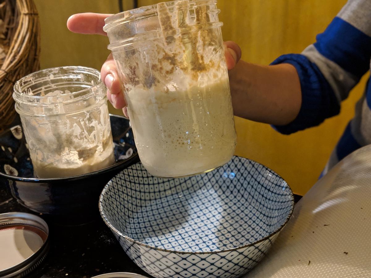Rosie holds up her sourdough starter, which is bubbling.