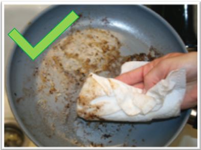 image of someone wiping a greasy pan with a paper towel