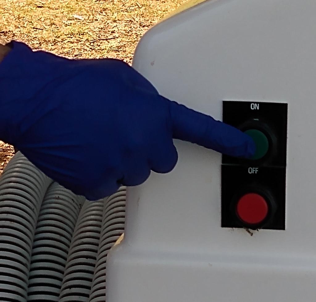 hand pressing the green button on the pump out system