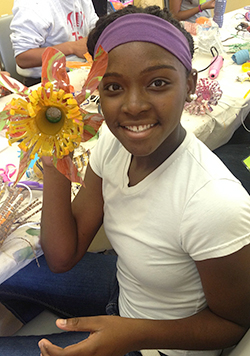 A young girl holding a flower created from recycled plastic bottles