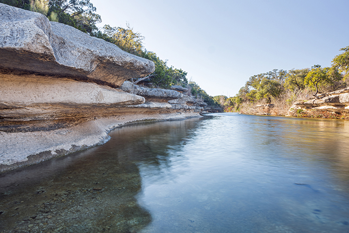 Canyon Rimrock.  This is a type of sheer rock wall, greater than 50 feet long and four feet tall.  That is next to a flowing creek.