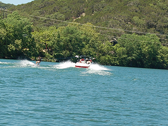 Citizens water skiing creating waves.