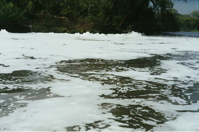 Foam accumulation in a waterway from an illegal discharge.