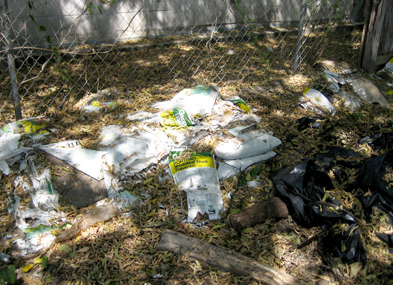 Improper disposal of herbicide (weed killer) on the ground adjacent to an alleyway.