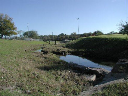 A heavily mowed, channelized creek exhibiting degraded riparian health.