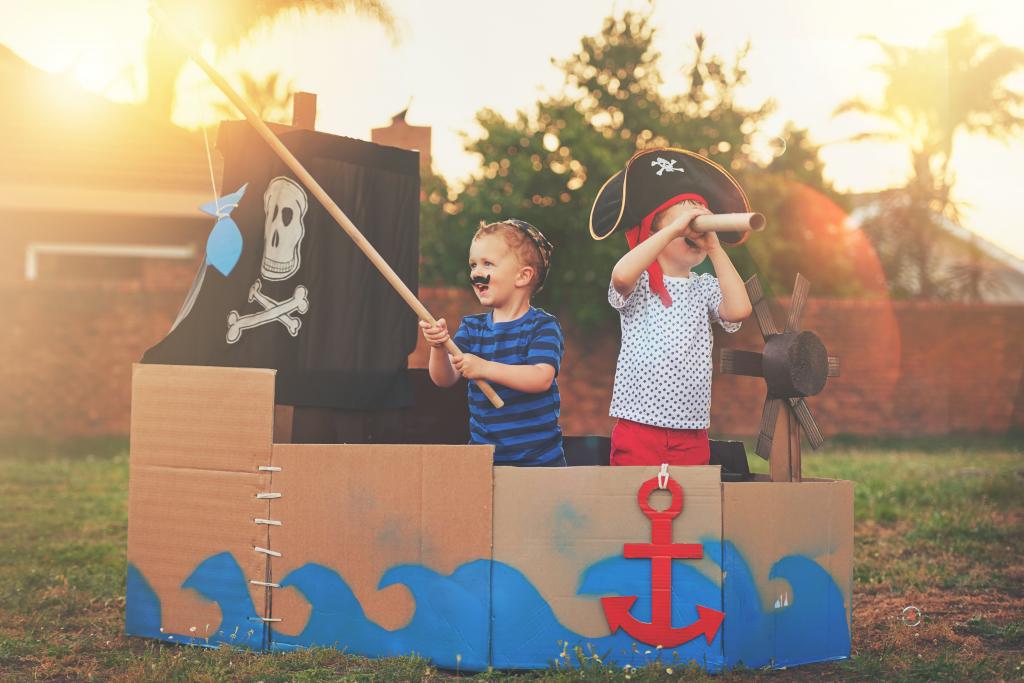 "children play in a pirate ship made out of cardboard boxes"
