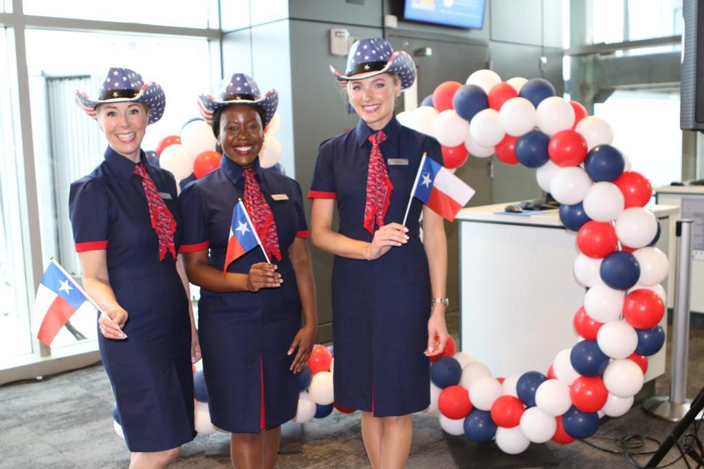 British Airways stewardesses hold little Texas flags as they pose for a picture during the AUS-BA 10 year anniversary celebration at AUS.