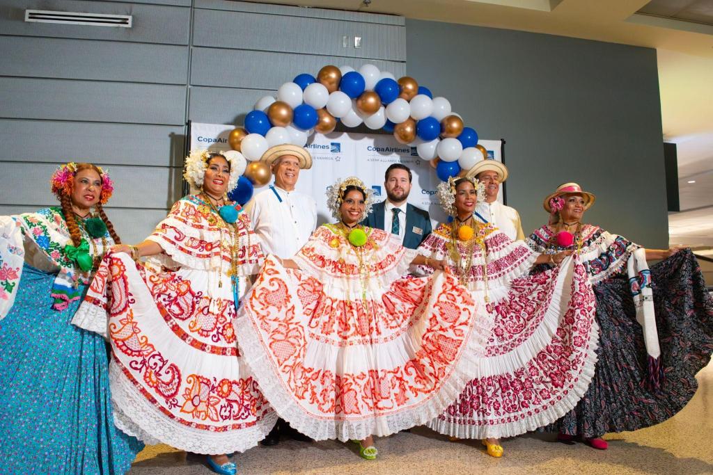 Bailarines panameños lucen su vestimenta frente a una pancarta de Copa Airlines