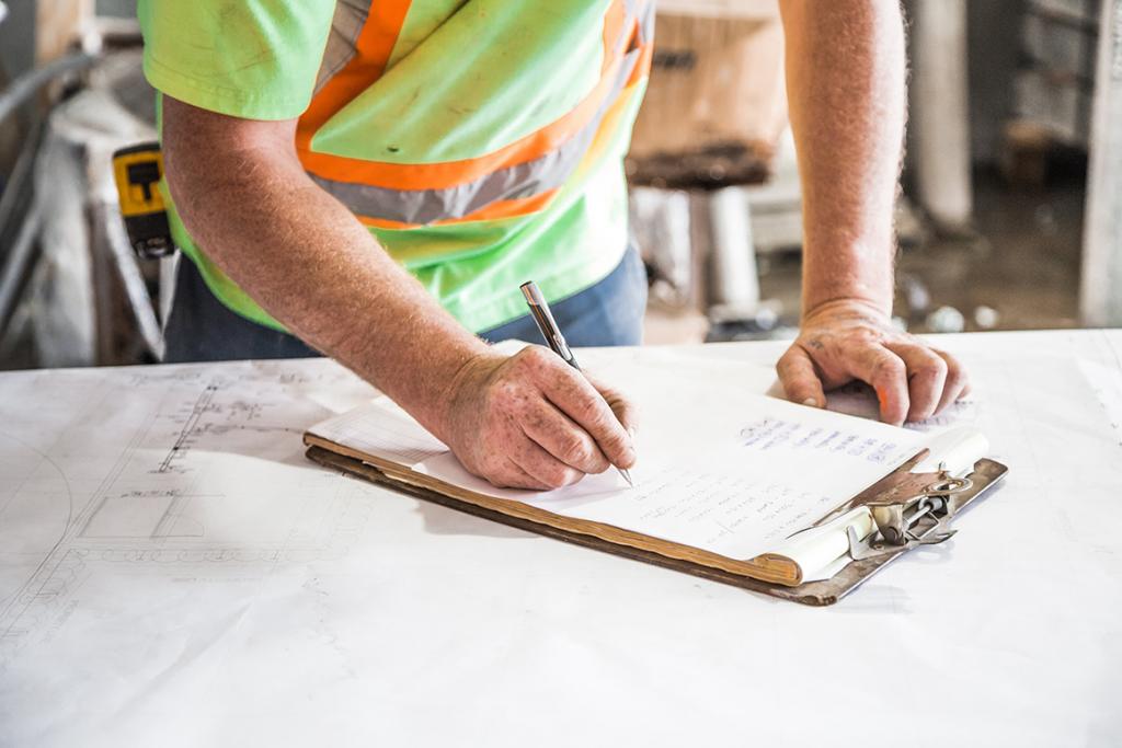 male construction worker writing on a piece of paper