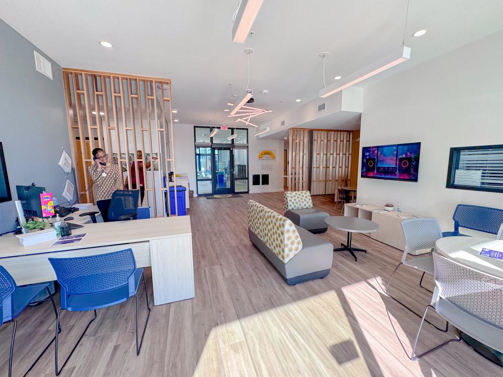 Modern leasing office lobby with front desk, lounge seating, and wood accents.