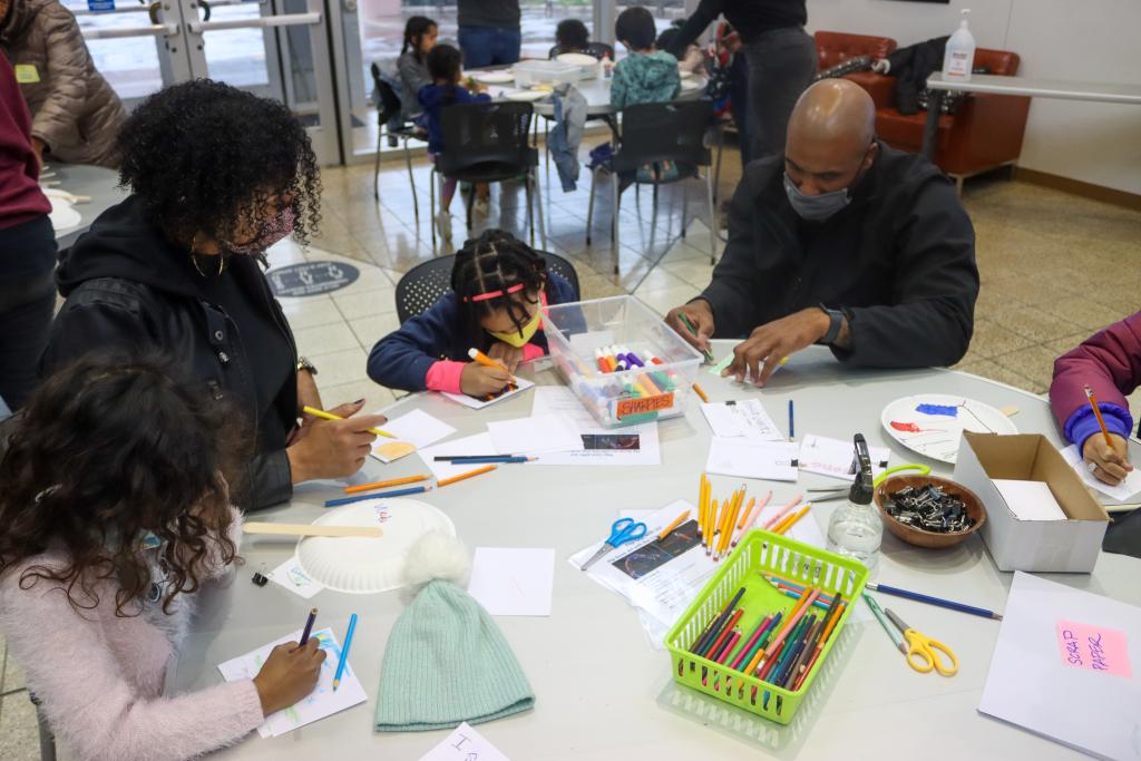 photograph of an adult showing a child how to create a craft