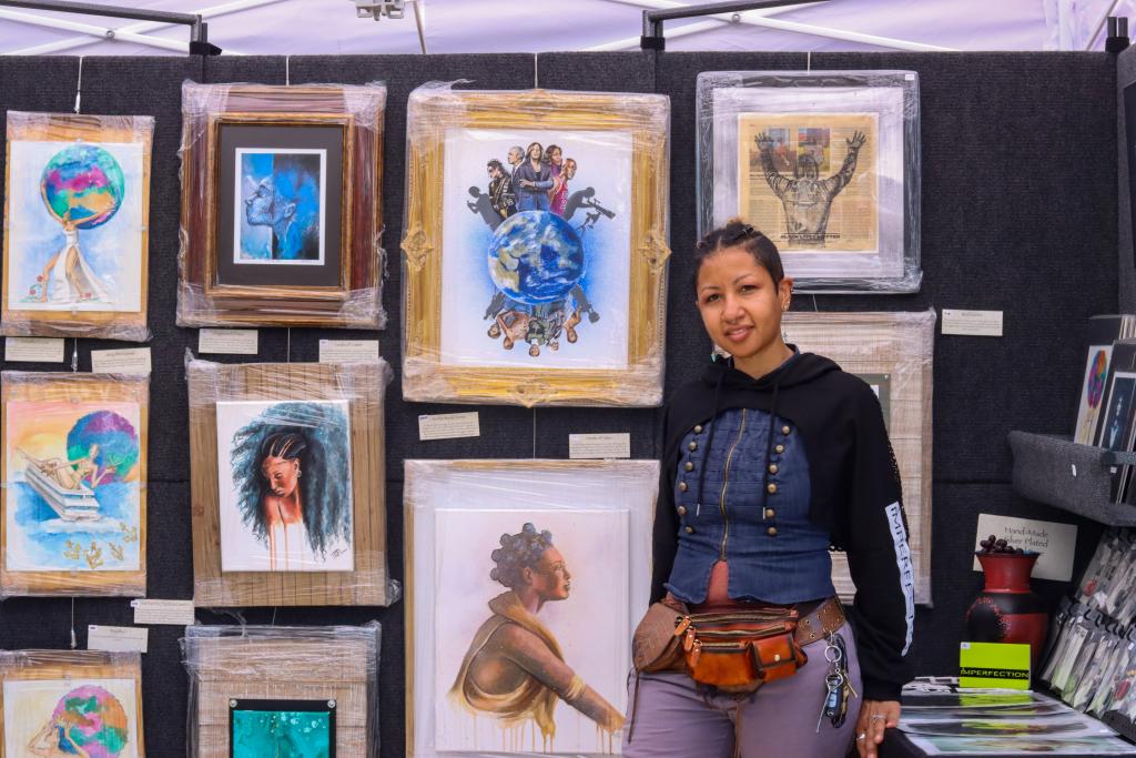 photograph of an artist in front of their paintings