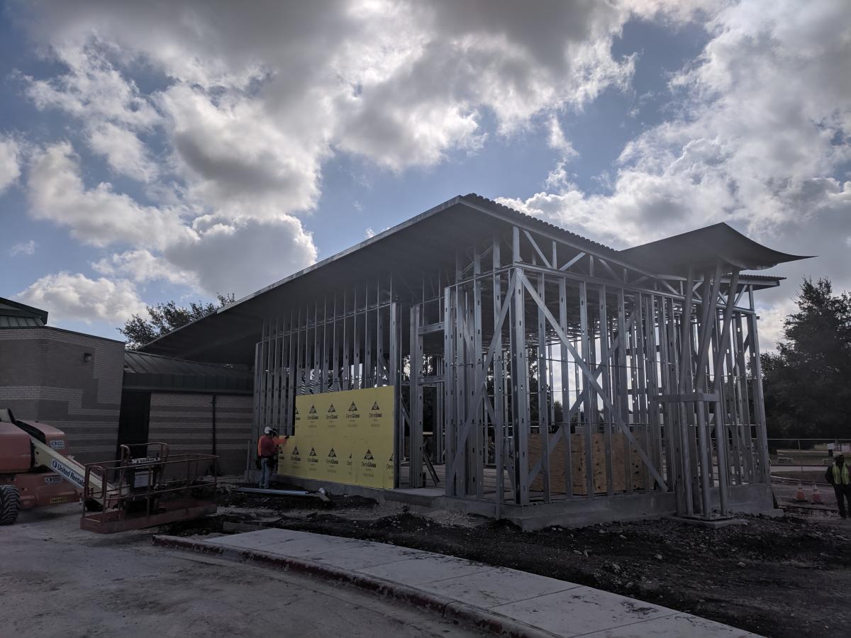 Dove Springs Recreation Center construction photo showing the framing going up with a beautiful cloud-filled sky in the background.