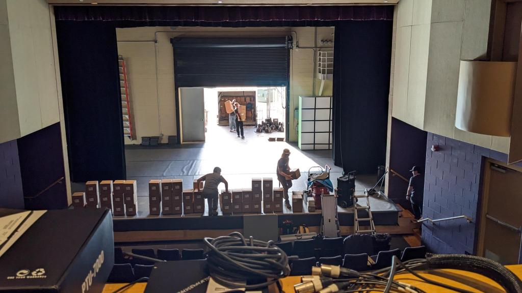 Image of theater showing beginning of renovation process with people moving boxes