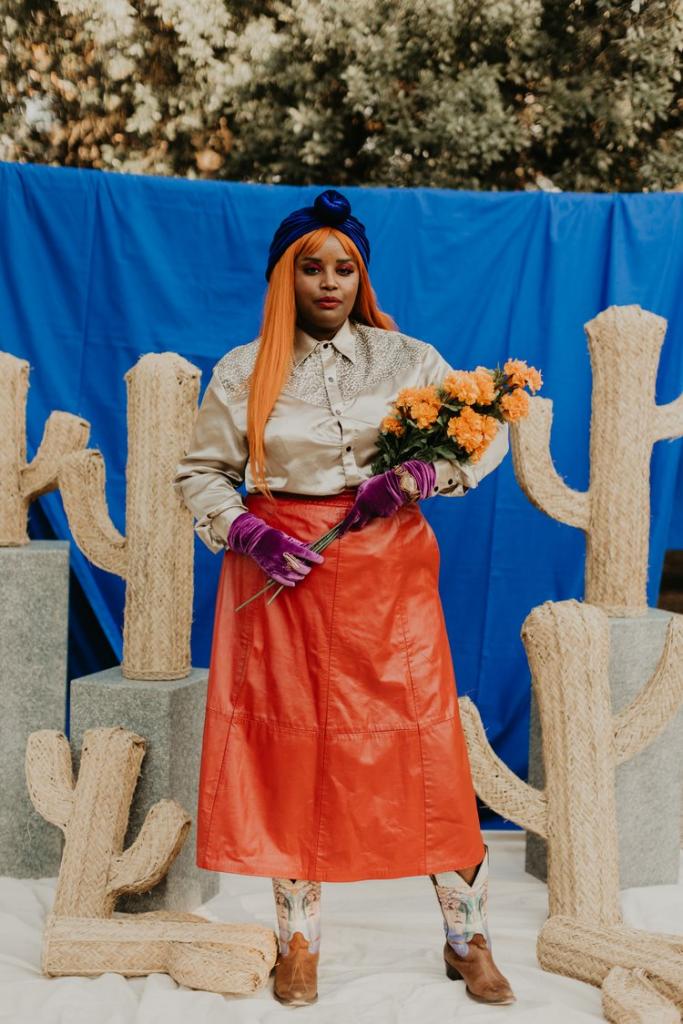 Woman in orange skirt, velvet gloves holding flowers