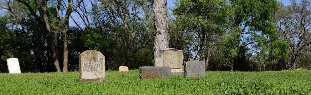 Image of Plummers Cemetery showing headstones with grass and trees in background
