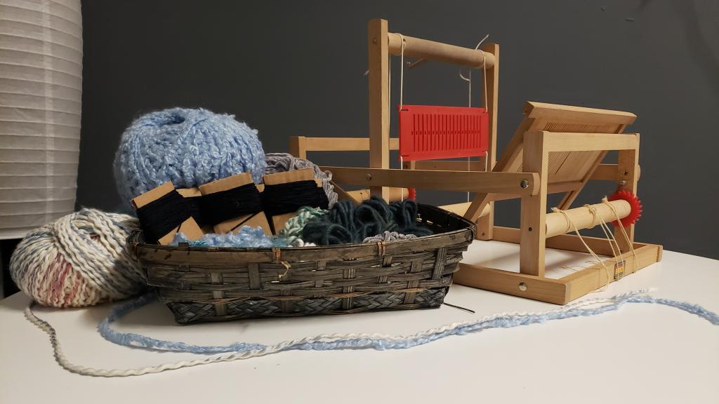 Weaving loom, yarn and other textile equipment rests on a table