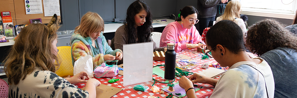 A group of people of various ages sitting around a table and working on art projects