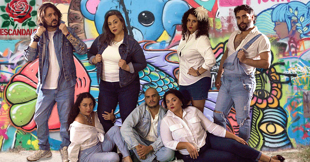 A photograph of seven people standing in a group and looking dramatic up against a graffiti wall the text 'Escandalo' is seen in the top left corner.