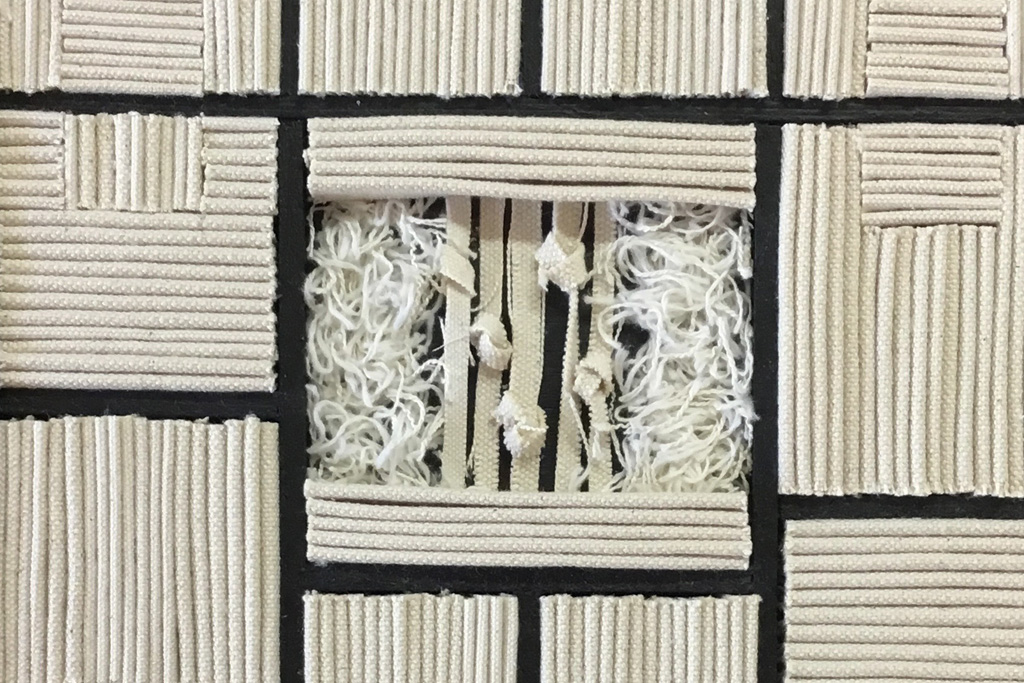 A photograph of a piece of artwork made up of cut pieces of rope arranged into squares.
