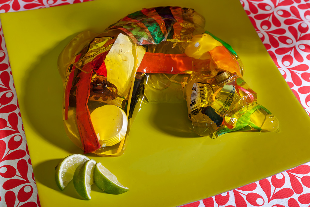 A photograph of a hello fish filled with trash on a serving plate with lime wedges