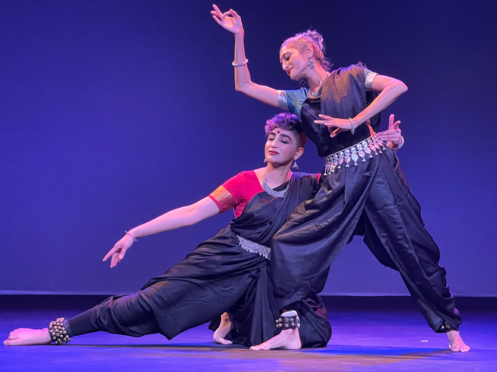 Two people performing a dance together with flowing gestures