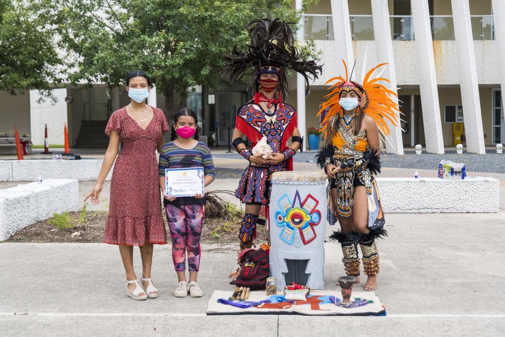 A student who participated in the Aztec Kids summer camp is given award by the Academia Cuauhtli instructors