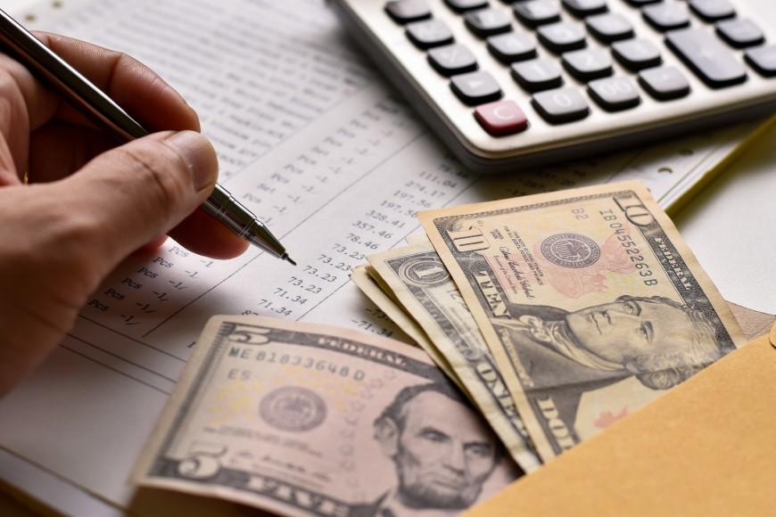 Stock photo of a person counting money and writing down numbers 