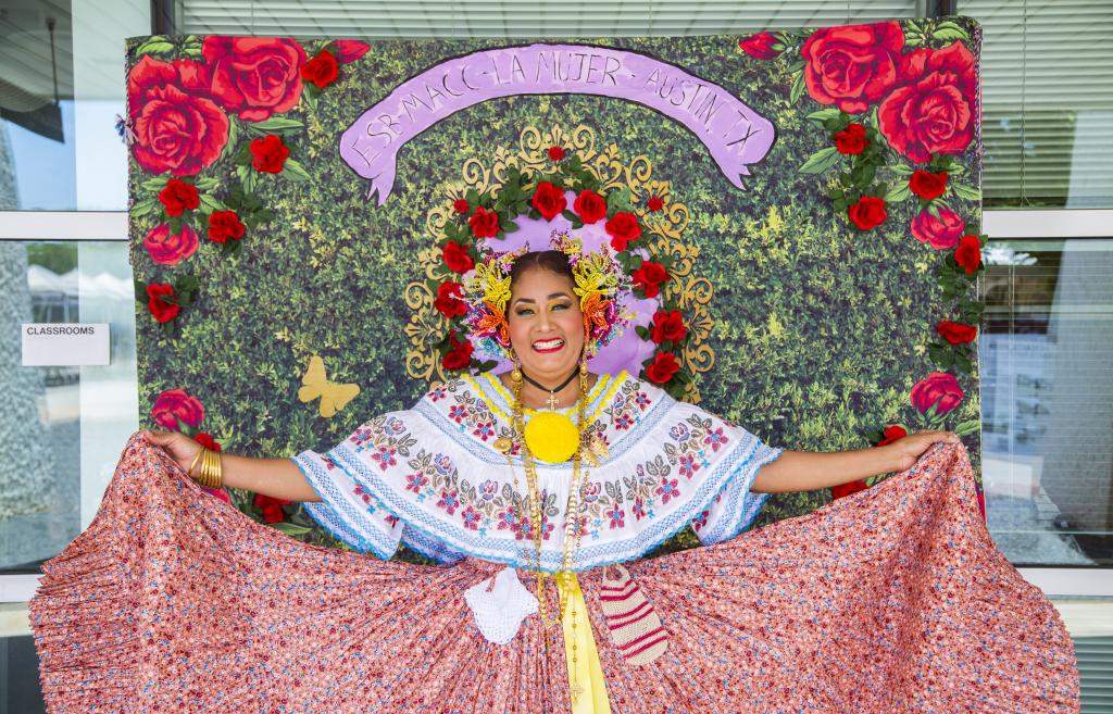 Photo of a member of Ballet Folklorico de Austin in front of a photo backdrop at Lu Mujer 2022