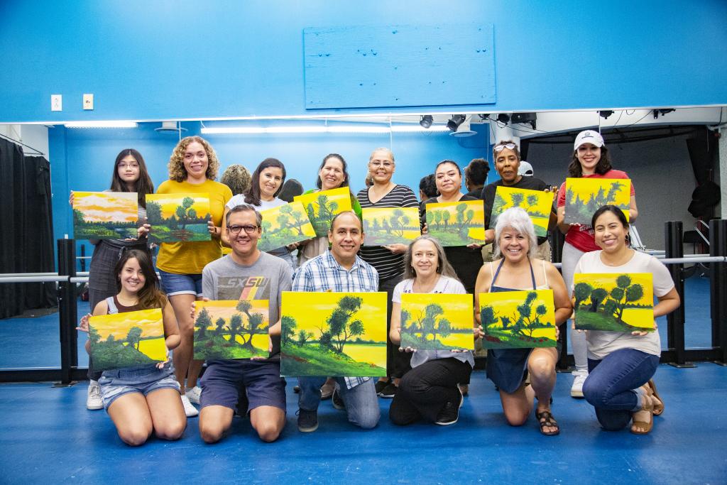 Photo of students showing off their paintings after their painting workshop