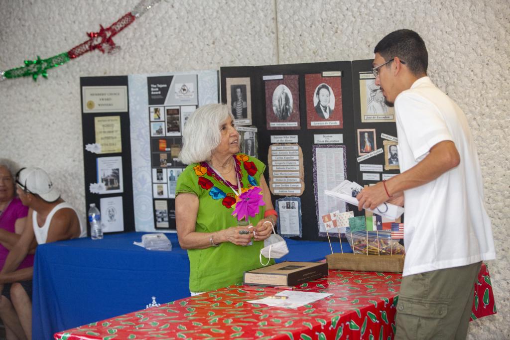 Photo of a Viva Mexico 2022 attendee talking to a representative of the Tejano Genealogy Society of Austin 