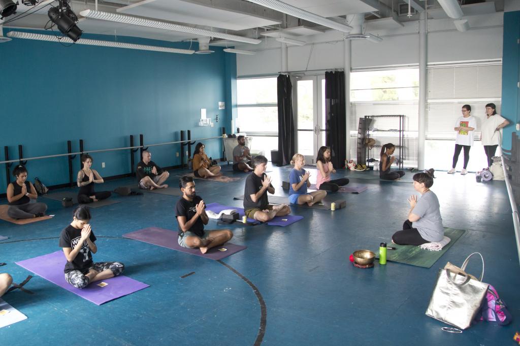 Photo of participants in a yoga pose at the ESB-MACC dance studio led by Sana Yoga