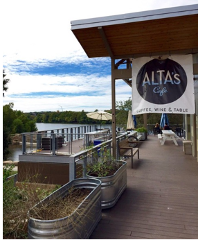 Image of deck of Waller Creek Boathouse with sign for the cafe and seating overlooking lake
