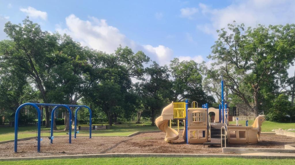 Rosewood Park playground with swings and boat theme play structure and trees in the background