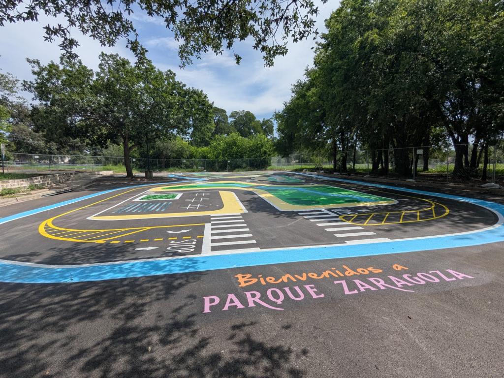 Photo of the finished placemaking project, showing games and a bike training course painted on a paved surface, along with the message "Bienvenidos a Parque Zaragoza"