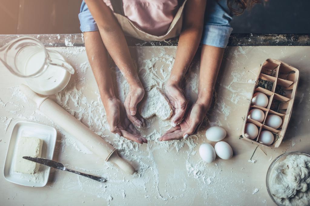 Image of people rolling dough together in kitchen