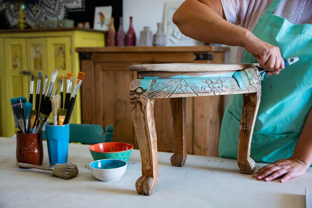 Image of person putting fresh turqouise paint over furniture item