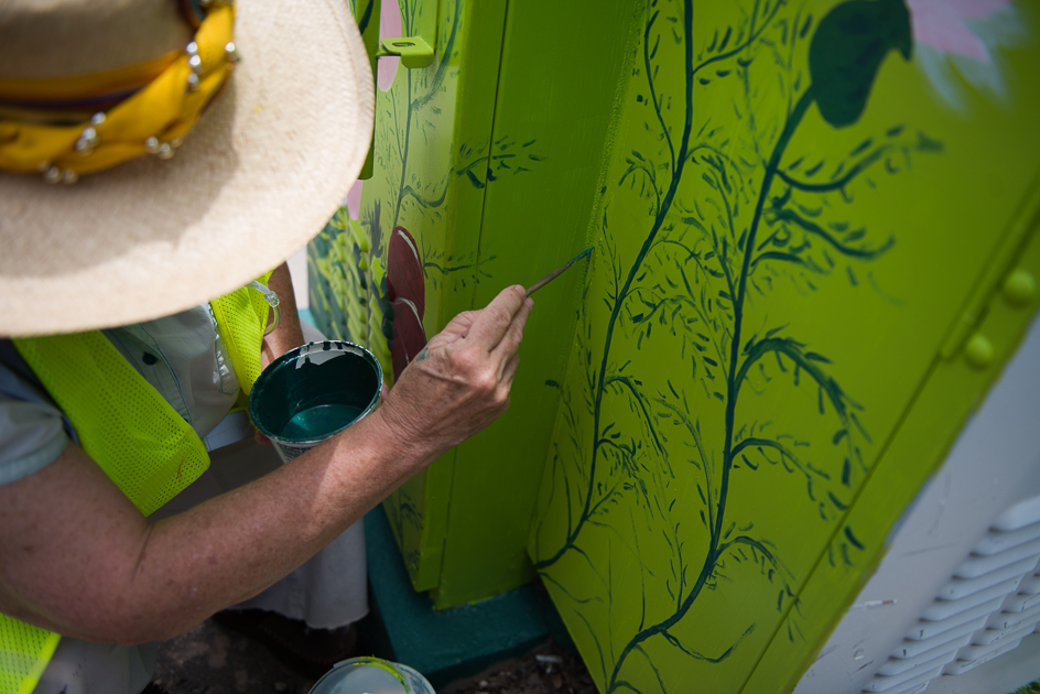 An artist paints a utility box in northwest Austin.
