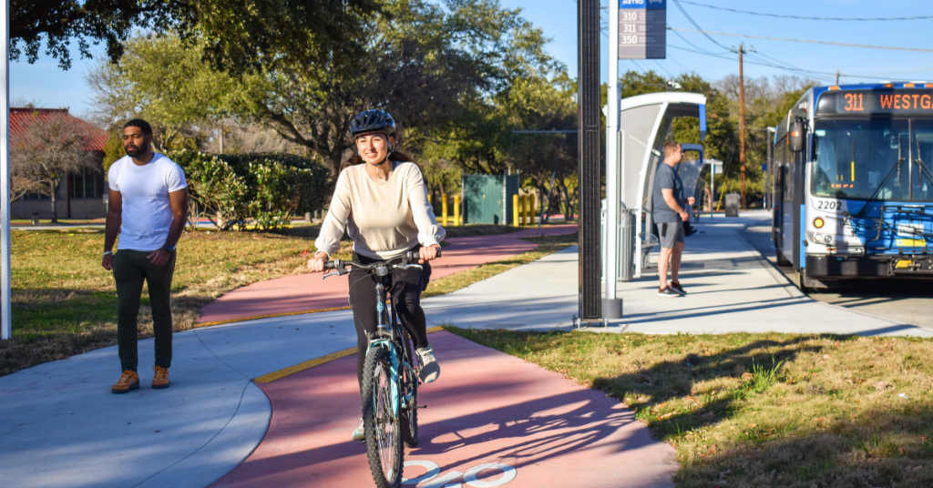 People walking, biking, and getting on a bus on a street in Austin. 