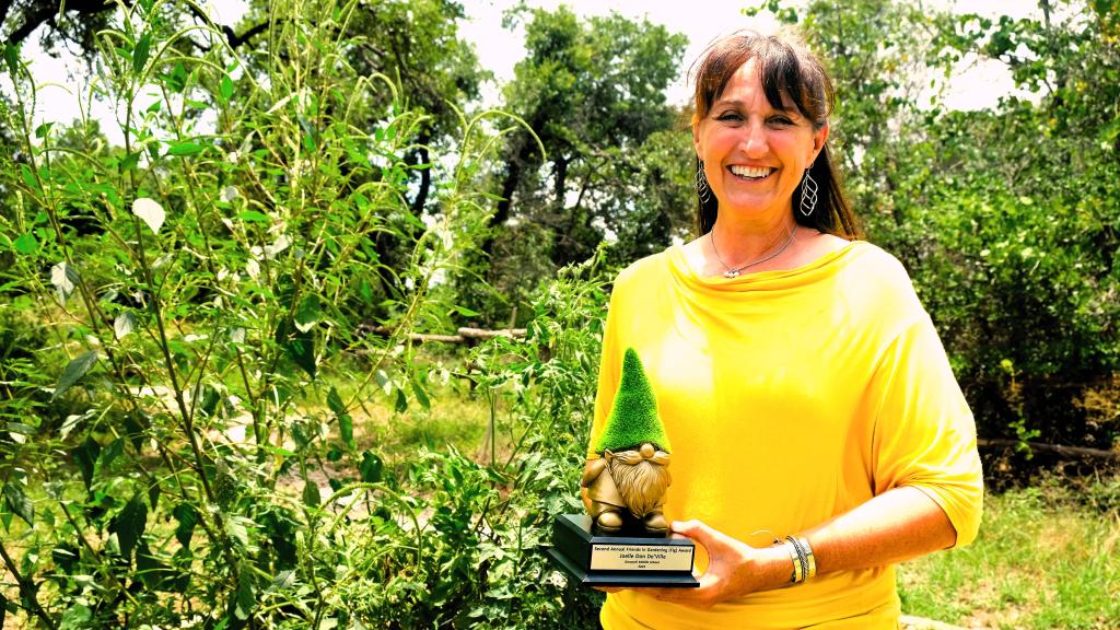 Joelle smiles with her golden gnome trophy in front of the AAA garden.