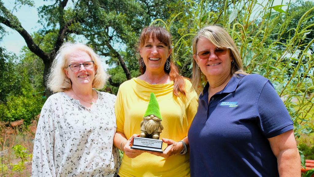 Carolyn Finkler, Joelle Don De’Ville, and Mary K. Priddy stand together in the Goryzcki gardens.