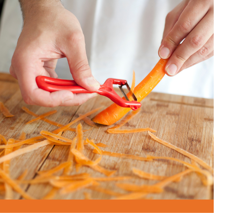 A close up of hands peeling carrots.