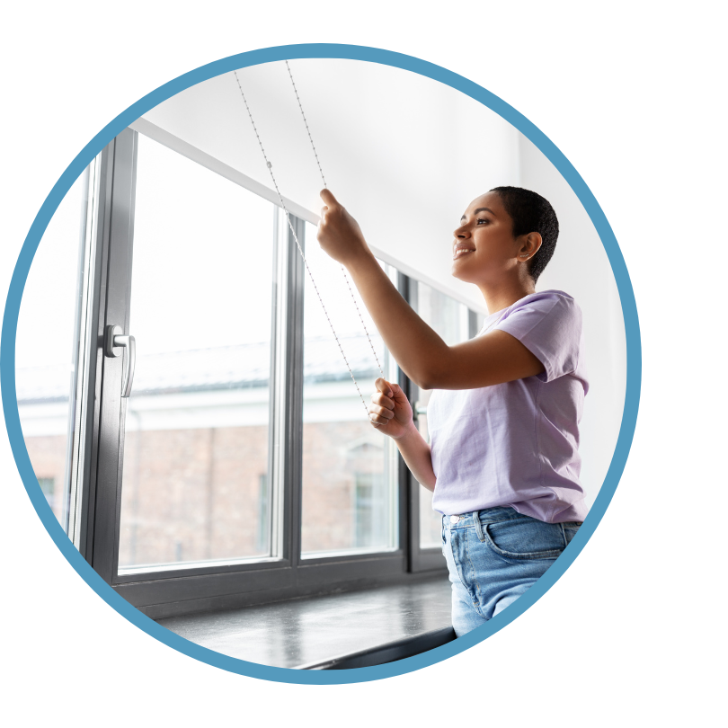 A woman lowers her blinds.