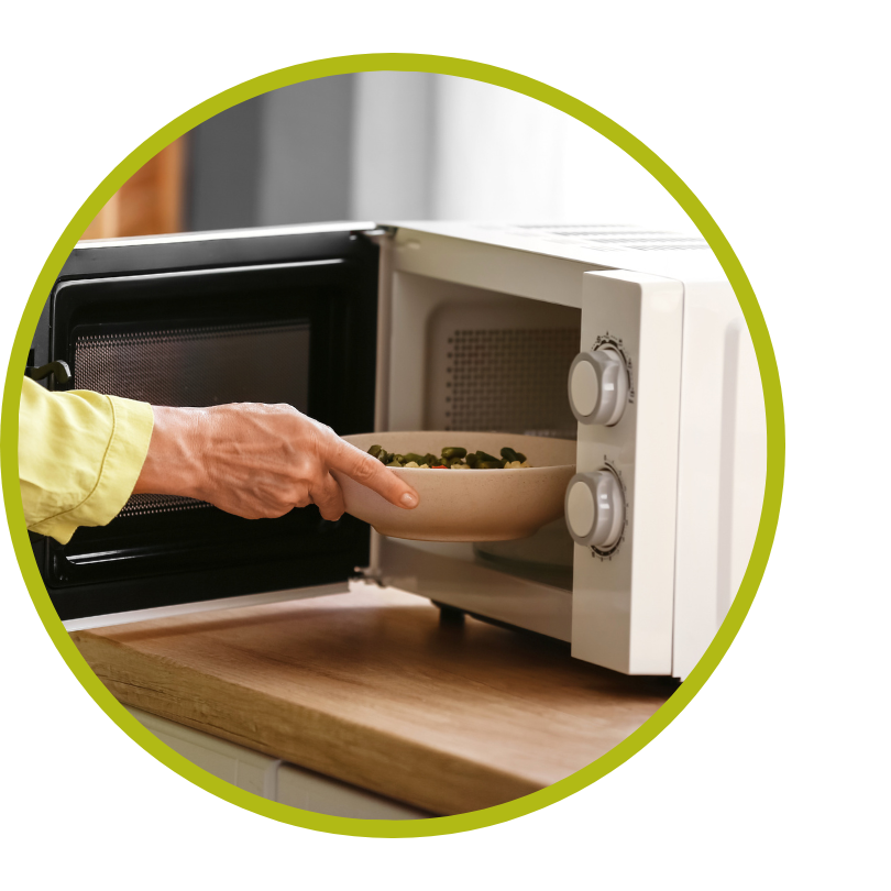 A close up of a hand putting food in a microwave.