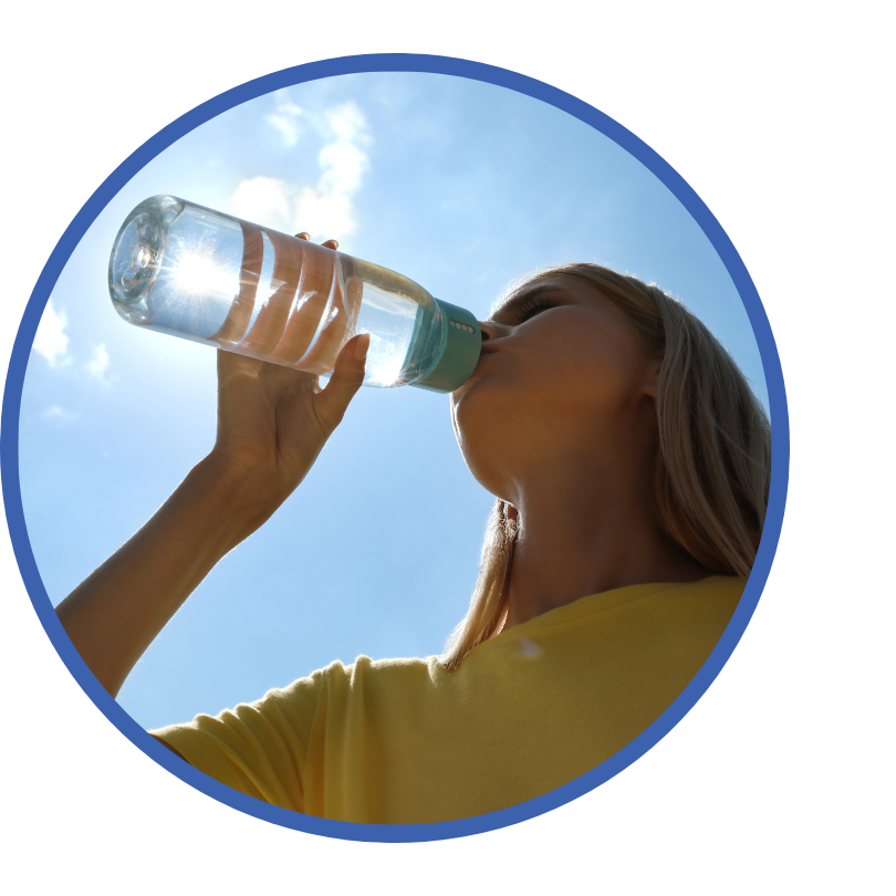 A girl drinks from a reusable water bottle with the sun behind her.