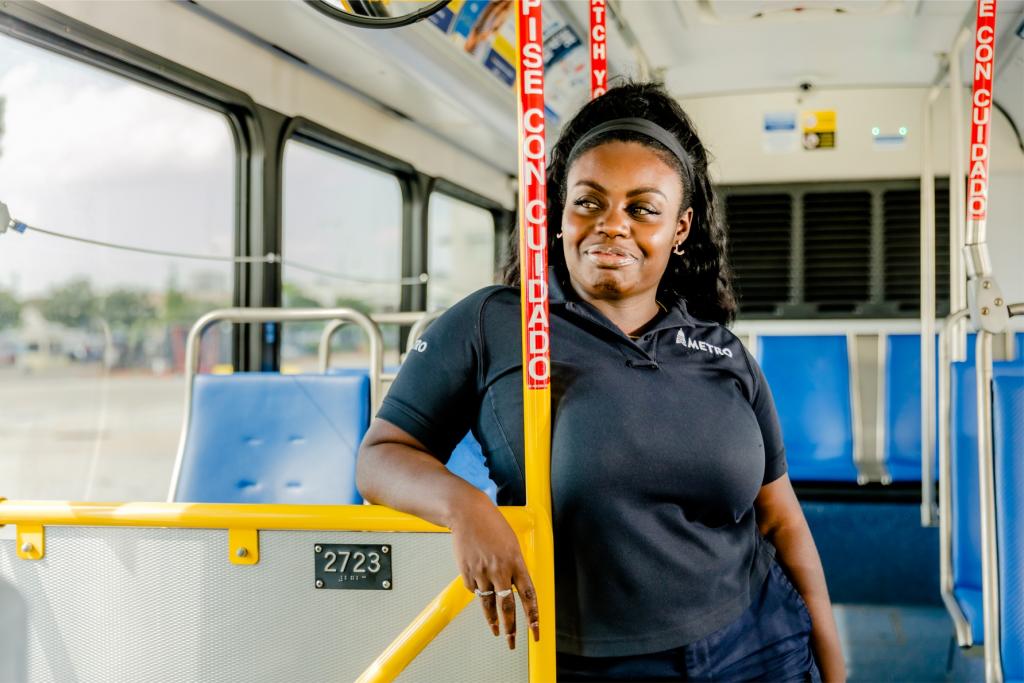 A Capital Metro worker smiles and looks out a bus window.