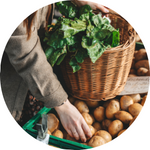 A photo of a woman picking up potatoes at an outdoor farmers' market.