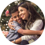 A photo of a woman and her son hugging in front of a Christmas tree.