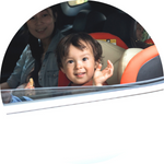 A photo of a young boy waving from a car window.