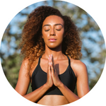 A photo of a woman meditating outside.